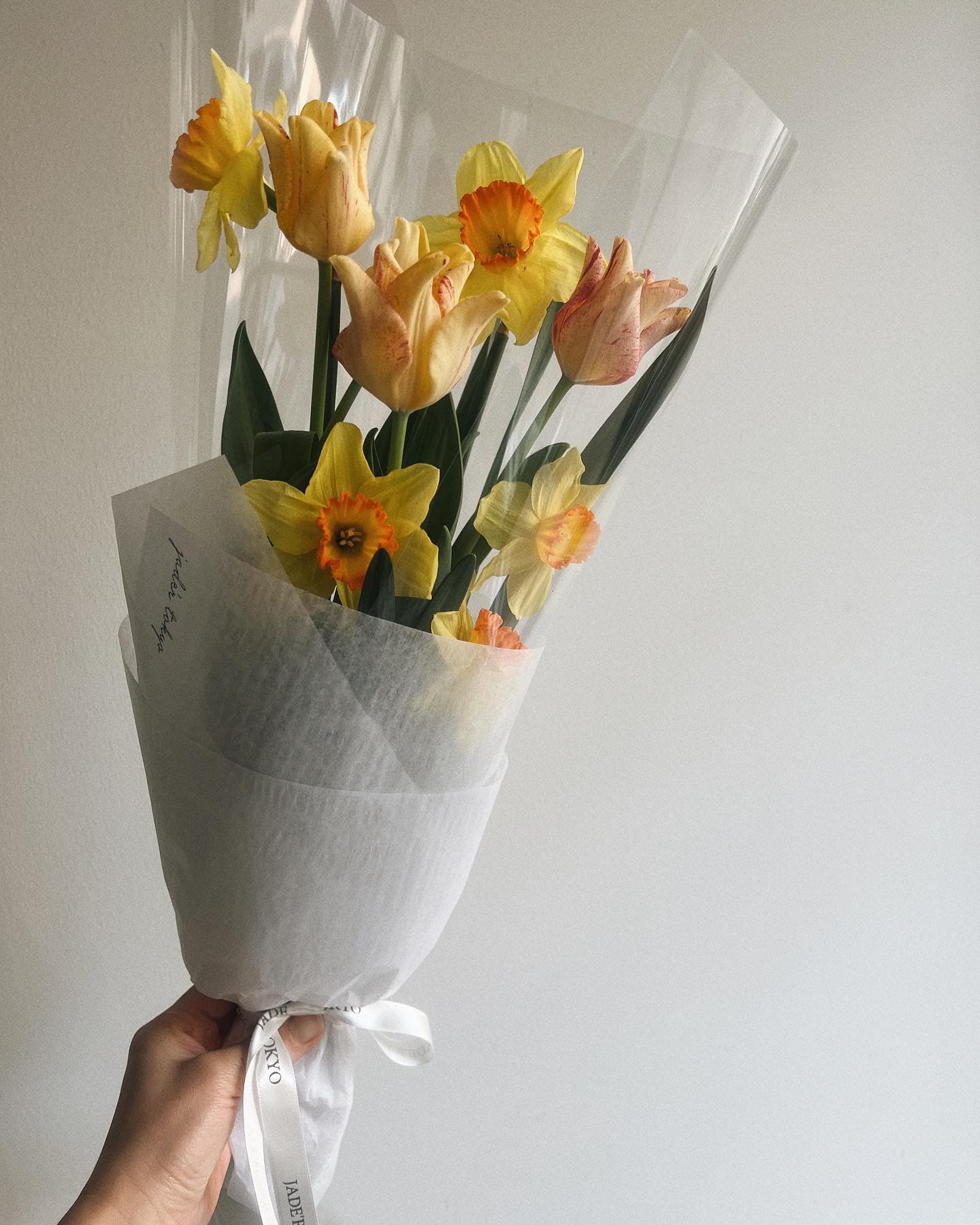 Ramo de flores amarillas, posiblemente tulipanes, envuelto y sostenido